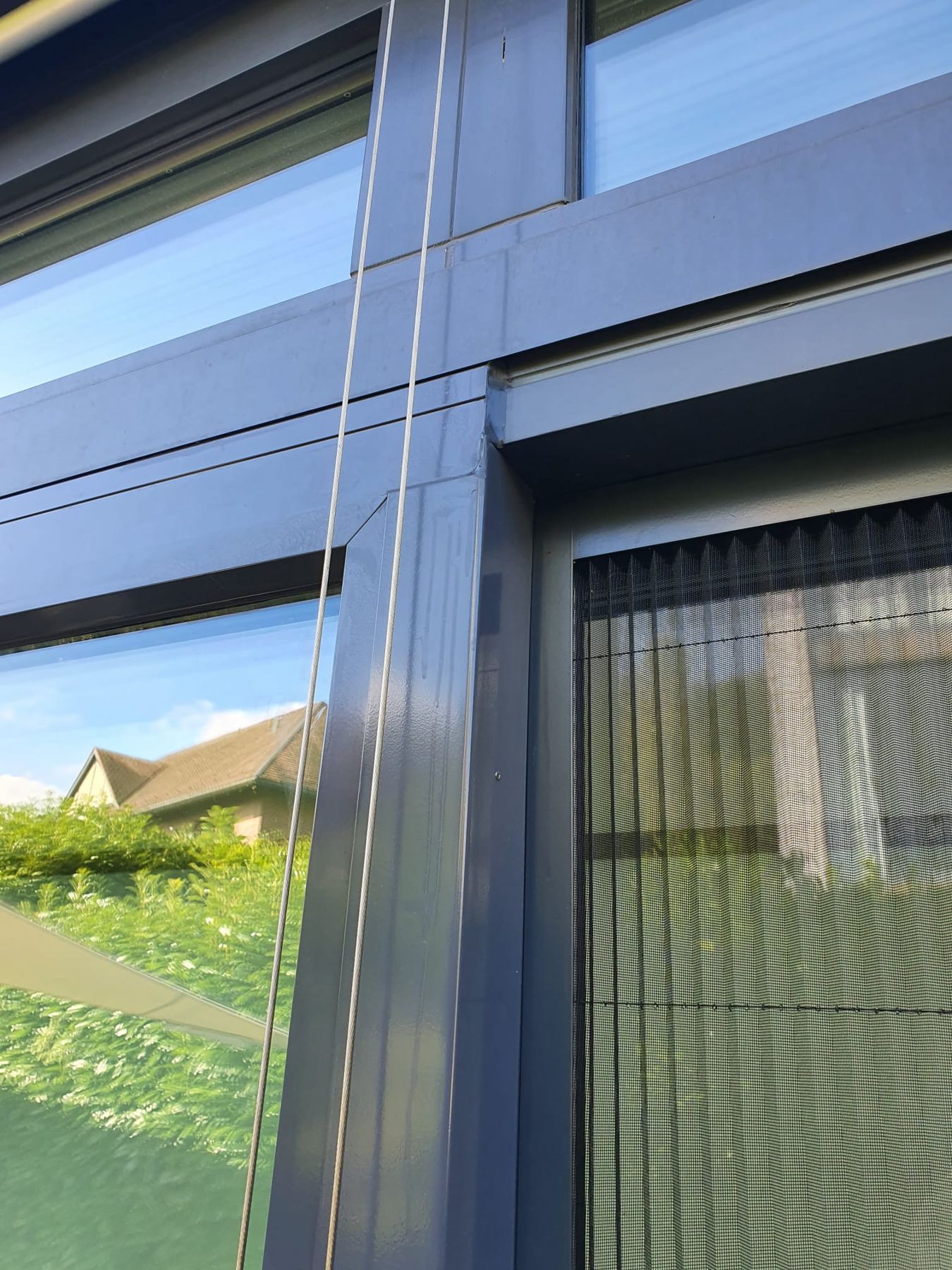 Fenster in einer grauen Fassade mit Plissee-Insektenschutz