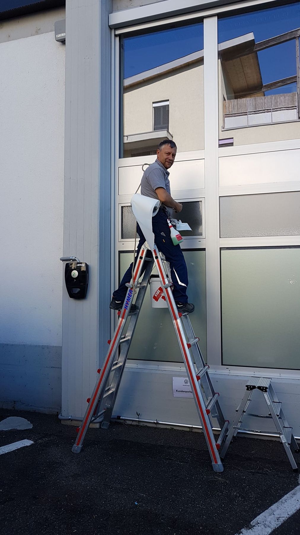 Servicemonteur auf der Leiter an einer Glasfront
