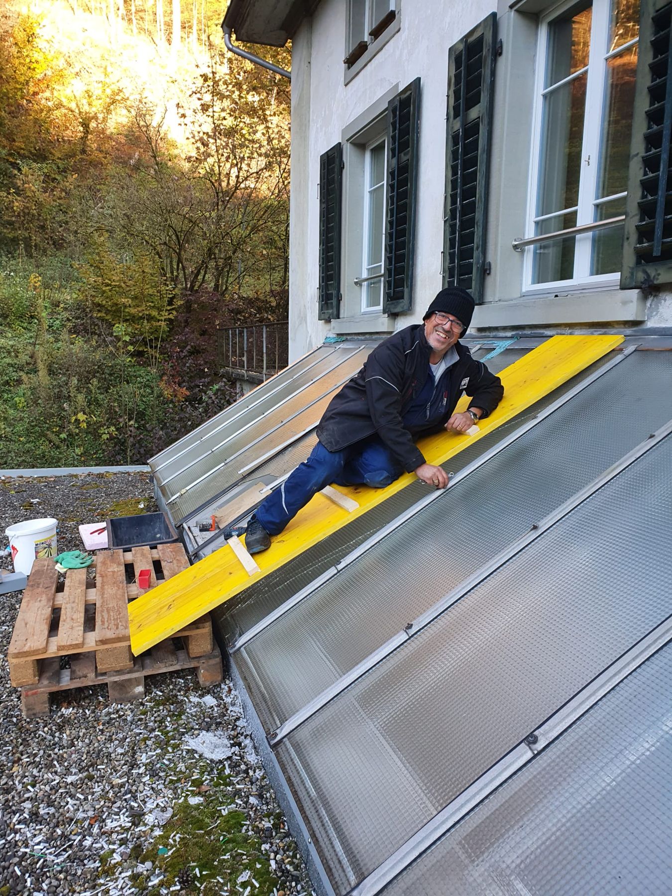 Servicemonteur auf Laufbrett beim Arbeiten an einem Glasdach